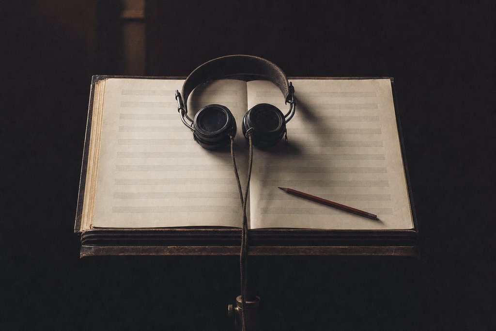 Headphones resting on an open conductor's score, a pencil across the page.