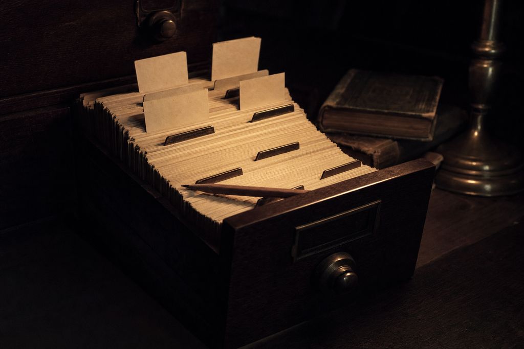 An open card-index drawer packed with plain unprinted cards, brass guides between them and a pencil resting across it
