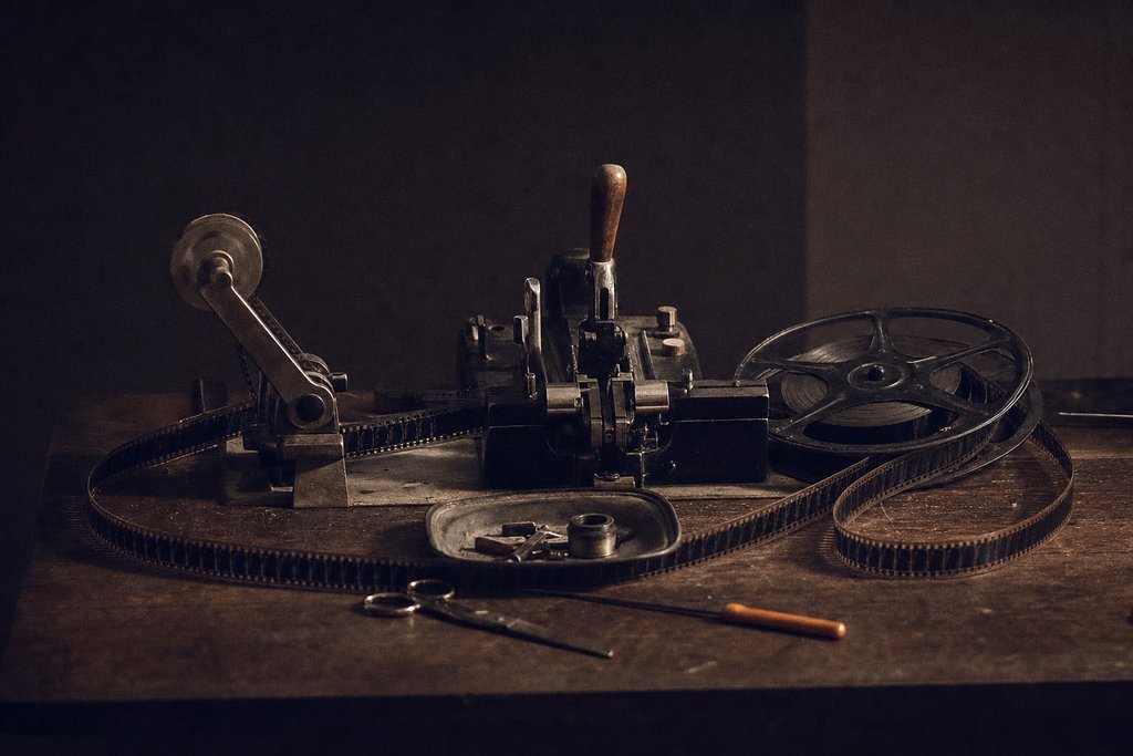 A film editing bench: a splicer, a rewind arm, an open reel of film looped across the bench.
